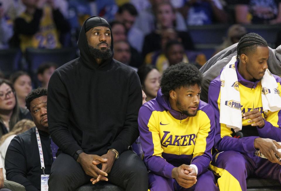 Lakers star LeBron James sits on the bench next to his son, Lakers guard Bronny James.