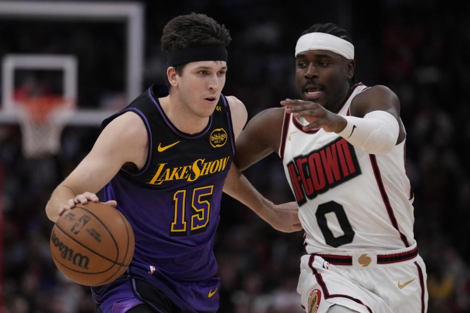 Lakers guard Austin Reaves, left, drives past Houston Rockets guard Aaron Holiday during the first half Sunday.