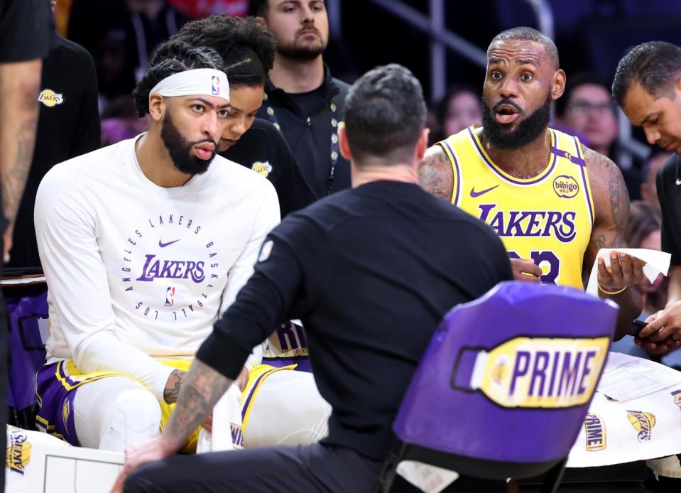 Lakers Anthony Davis, left, and LeBron James, right listen to coach JJ Redick during a timeout at Crypto.com Arena.