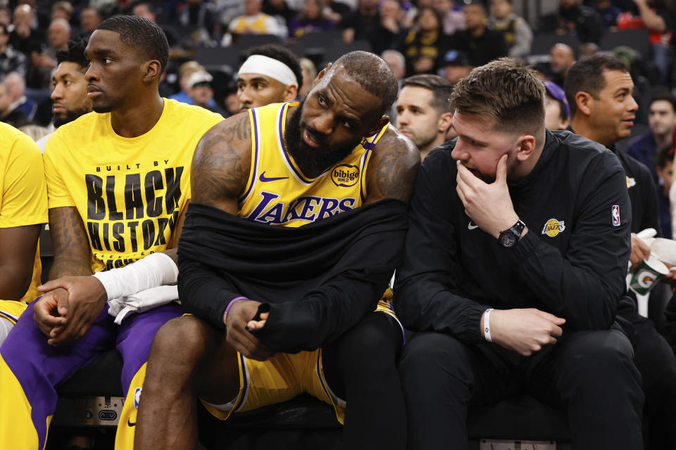 Los Angeles Lakers guard Luka Doncic, right, talks to forward LeBron James on the bench before an NBA basketball game against the Los Angeles Clippers, Tuesday, Feb. 4, 2025, in Inglewood, Calif. (AP Photo/Kevork Djansezian)