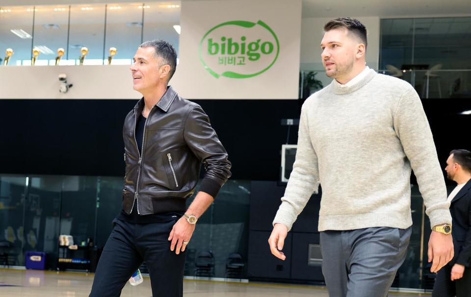 Lakers general manager Rob Pelinka, left, walks alongside side newly acquired Lakers star Luka Doncic.