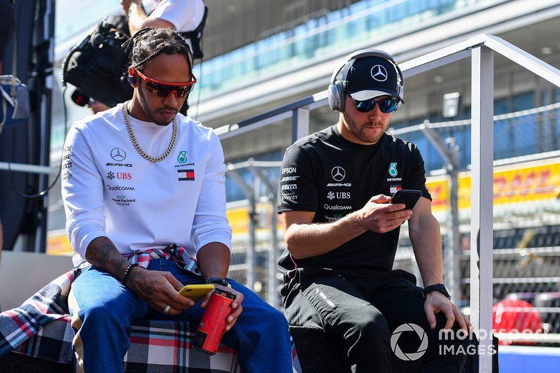 Lewis Hamilton, Mercedes AMG F1, and Valtteri Bottas, Mercedes AMG F1, look at their phones