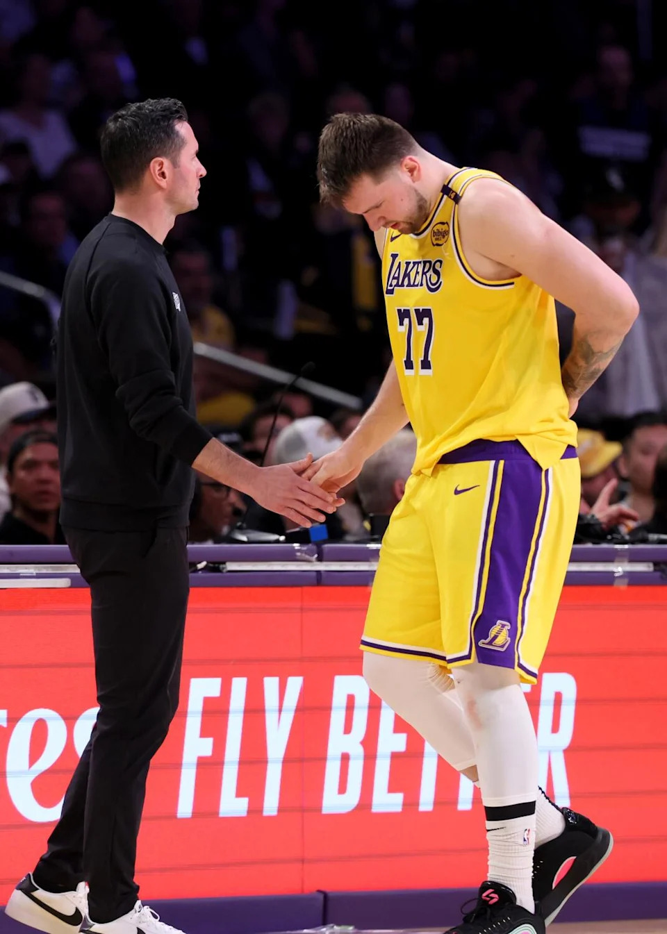 Lakers coach JJ Redick, left, slaps hands with guard Luka Doncic as he walks off the court after injuring his back in Game 5.