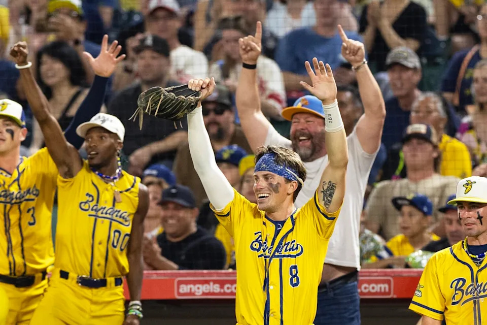 The Savannah Bananas' Jackson Olson and teammates raise their arms celebrates a Troy Glaus base hit.