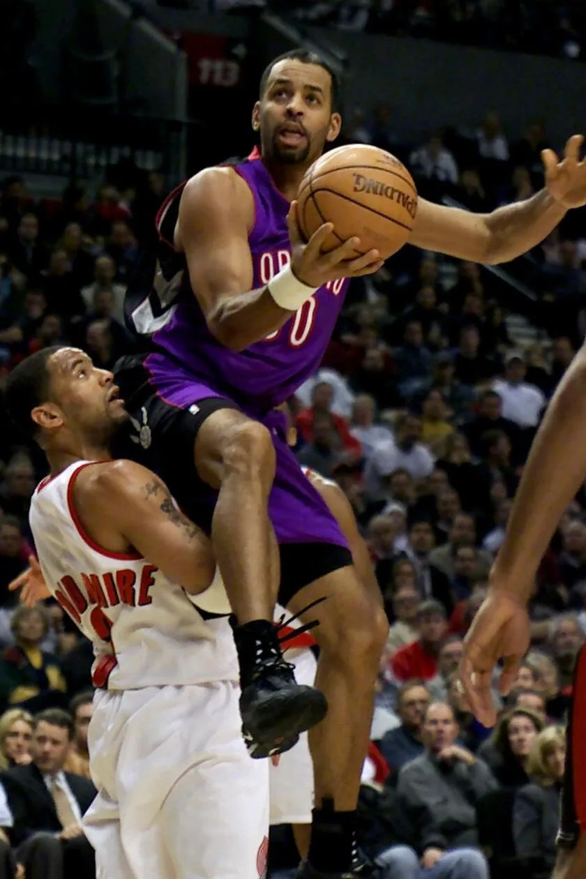 Toronto Raptors' Dell Curry lands on top of Trail Blazers' Damon Stoudamire as he drives to the hoop.