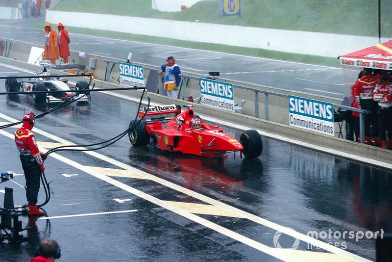 Michael Schumacher, Ferrari F300, with missing front wheel and wing, and David Coulthard, McLaren MP4-13 Mercedes, with missing rear wing, in the pitlane