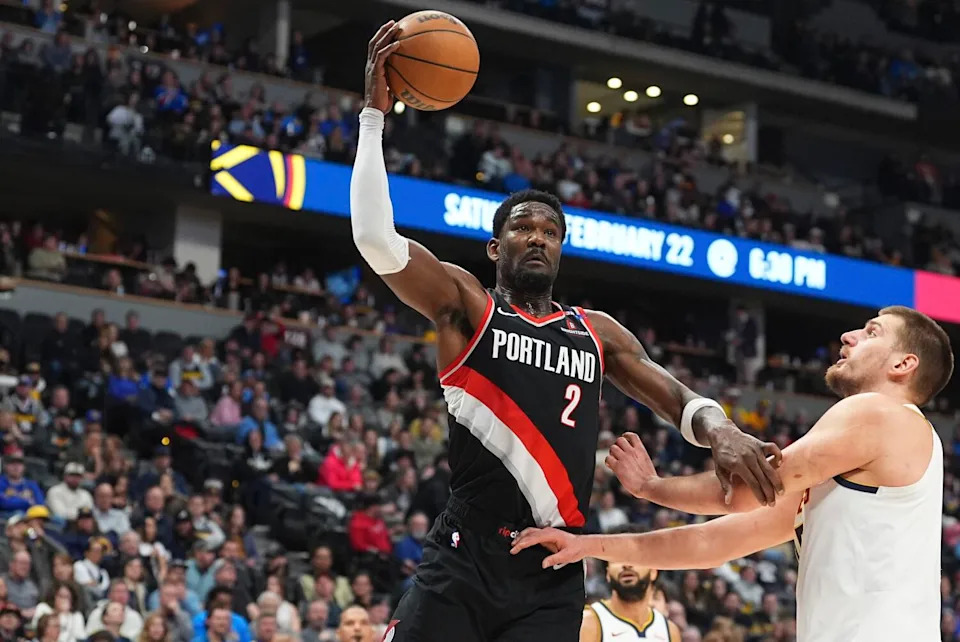 Portland Trail Blazers center Deandre Ayton, left, tries to drive past Denver Nuggets center Nikola Jokic.
