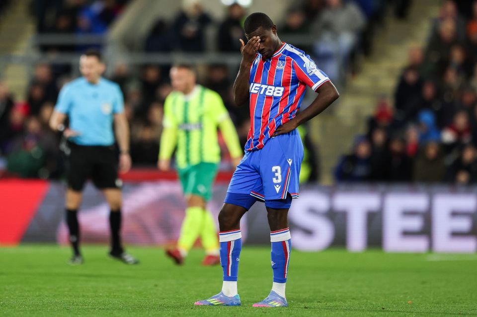 A Crystal Palace player in a red and blue striped jersey with number 3 on his shorts, holding his head with his hand in disappointment.
