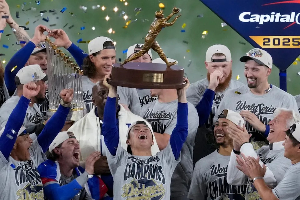LA Dodgers World Series MVP Yoshinobu Yamamoto holds his trophy as teammates celebrate their win. AP