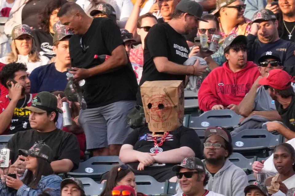 A fan wears a bag over his head that says "Sell the Team Arte!!!" during a game against the Rangers on Friday.